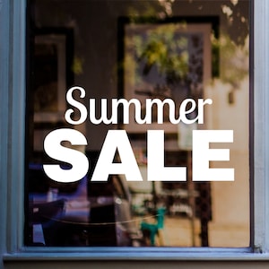 May include: A white sign with the text "Summer Sale" on a storefront window.