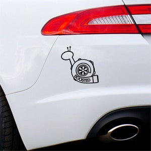 May include: A black and white decal of a snail with a turbocharger shell and the word "BOOSTED" underneath. The decal is applied to the back of a white car.
