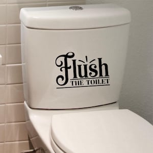 May include: White toilet with a black vinyl decal that says "Flush the Toilet" in a decorative font.