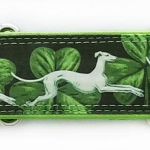 May include: A 1.5-inch wide dog collar featuring a repeating pattern of white greyhounds running across a black background with green shamrocks. The collar includes silver-toned metal hardware and a lime green satin lining along the edges.
