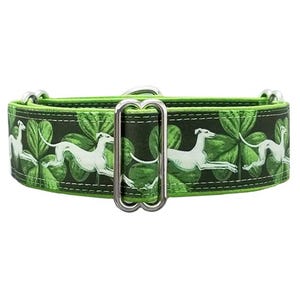 May include: A green dog collar featuring a repeating pattern of white greyhounds in a running pose against a background of green shamrocks. The collar includes a silver-toned metal adjustment slider and D-ring hardware for secure fastening.