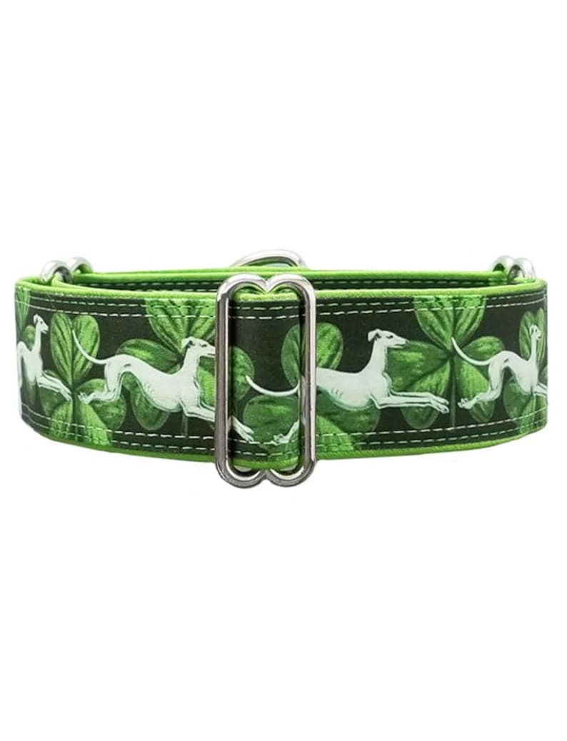 May include: A green dog collar featuring a repeating pattern of white greyhounds in a running pose against a background of green shamrocks. The collar includes a silver-toned metal adjustment slider and D-ring hardware for secure fastening.