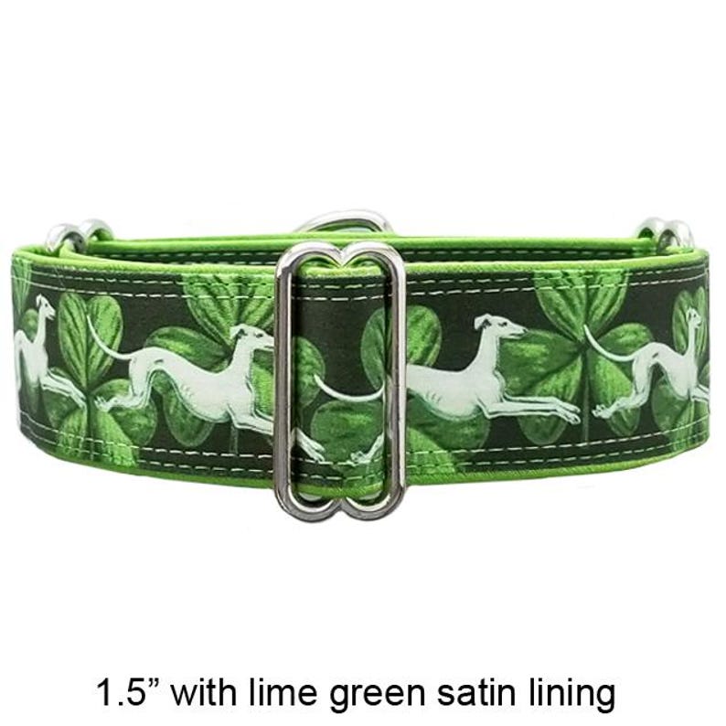 May include: A 3.8 cm wide dog collar featuring a dark green background with a repeating pattern of white greyhounds and green shamrocks. The collar includes a silver metal slider and D-ring hardware, finished with a lime green satin lining.