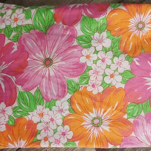 May include: A pink and orange floral fabric with a white background. The fabric features large pink and orange flowers with green leaves and smaller white flowers.