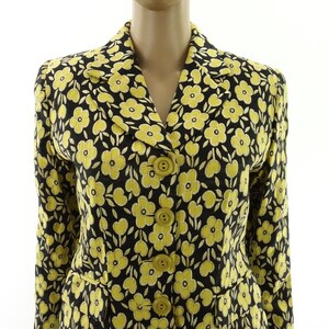 Puede incluir: Una chaqueta negra con estampado floral amarillo, con cierre de botones y mangas largas.