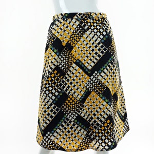 May include: A black, white and yellow patterned skirt with a geometric design. The skirt is knee-length and has a flared silhouette.