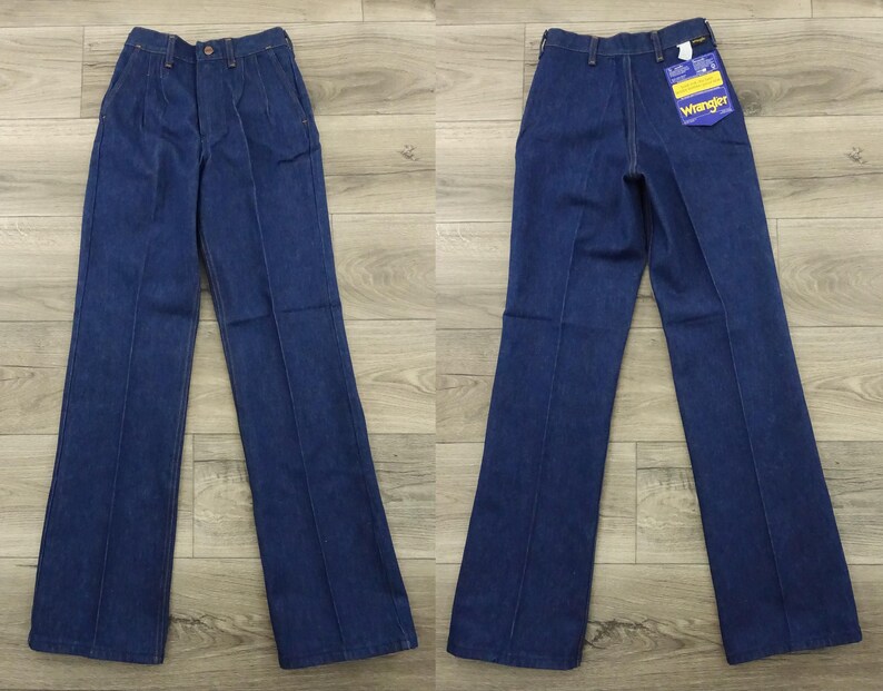 May include: A pair of dark blue denim jeans with a wide leg and a straight fit. The jeans have a button fly and belt loops. The jeans have a Wrangler label on the back pocket.