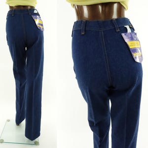 May include: A pair of dark blue denim jeans with a wide leg. The jeans have a high waist and a classic five-pocket style. The jeans have a Wrangler brand tag attached to the back pocket.