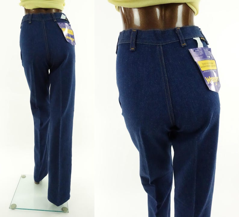 May include: A pair of dark blue denim jeans with a wide leg. The jeans have a high waist and a classic five-pocket style. The jeans have a Wrangler brand tag attached to the back pocket.