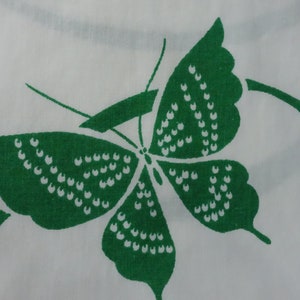 May include: A green butterfly with white dots on a white background. The butterfly is stylized and has a simple design.