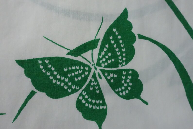 May include: A green butterfly with white dots on a white background. The butterfly is stylized and has a simple design.