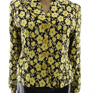 Puede incluir: Una chaqueta negra con estampado floral amarillo y cierre de botones.