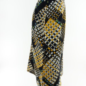 May include: A black and yellow skirt with a geometric pattern. The skirt has a straight silhouette and a mid-length hem.
