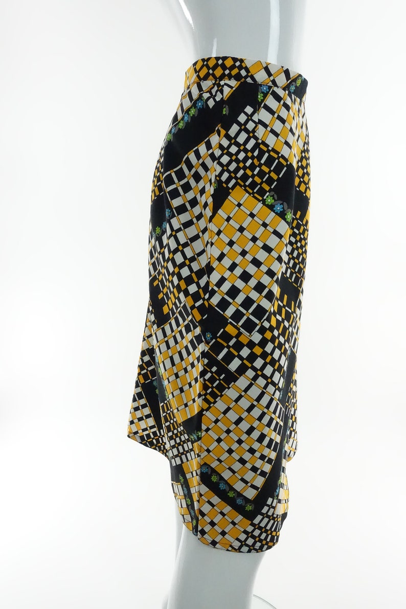 May include: A black and yellow skirt with a geometric pattern. The skirt has a straight silhouette and a mid-length hem.