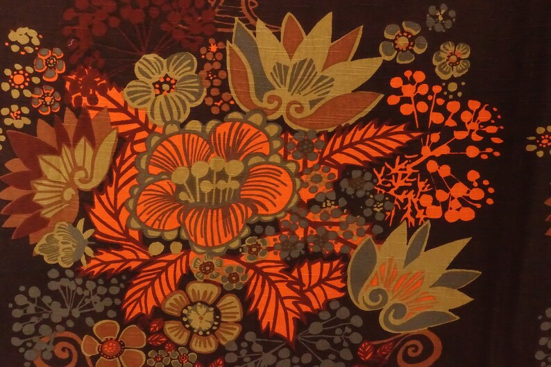 May include: A brown fabric with a floral pattern in shades of orange, brown, and green. The flowers are stylized and have a retro feel.