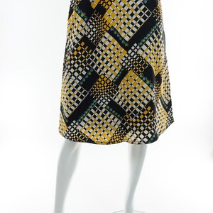 May include: A black, white, and yellow patterned skirt with a geometric design. The skirt is knee-length and has a straight silhouette.