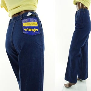 May include: A pair of dark blue denim jeans with a wide leg. The jeans have a label on the back pocket that says "Wrangler" and "Boot cut, flares, standard fit, jean style".