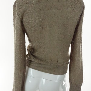 May include: A brown knitted sweater with a loose fit and long sleeves.
