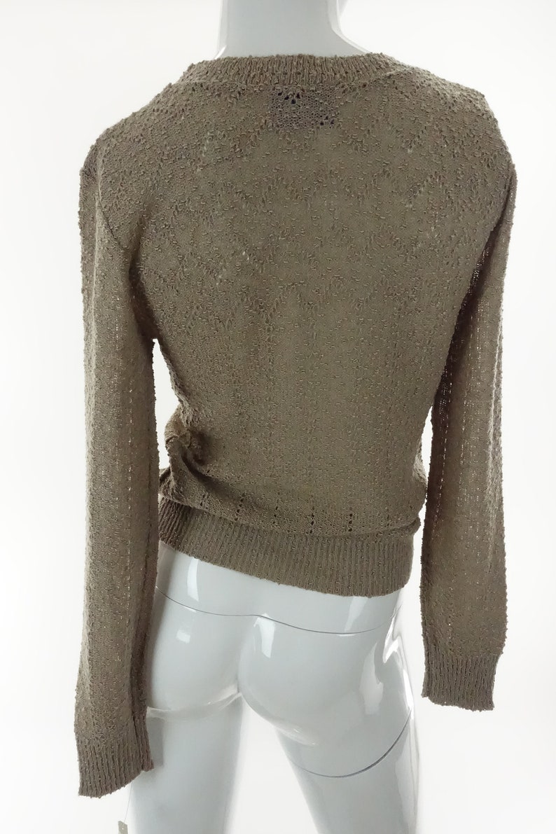 May include: A brown knitted sweater with a loose fit and long sleeves.