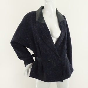 May include: A navy blue blazer with a black leather collar and a double-breasted closure. The blazer has a belt at the waist and a speckled pattern.