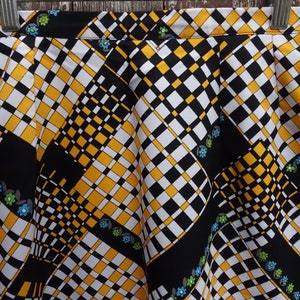 May include: A black, white, and yellow checkered skirt with a geometric pattern and small blue, green, and white flowers.