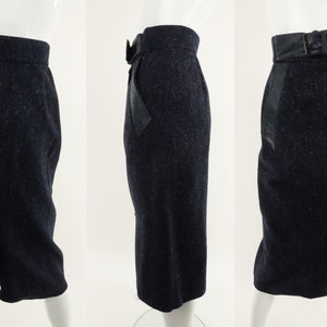 May include: A black skirt with a speckled pattern and a black leather belt. The skirt has a back slit and leather panels on the sides.