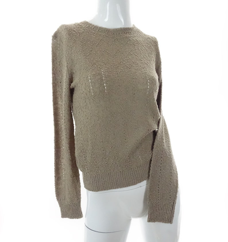 May include: A light brown, long-sleeved sweater with a loose, open knit pattern.