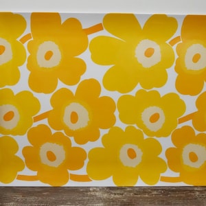 May include: A rectangular serving tray featuring a repeating pattern of large, stylised yellow flowers with white centres on a white background. The tray has slightly curved sides and a smooth, flat surface with a vibrant, high-contrast floral design.