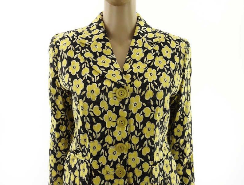 Puede incluir: Una chaqueta negra con estampado floral amarillo, con cierre de botones y mangas largas.