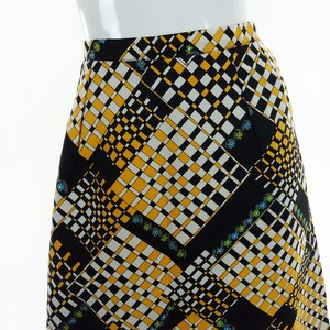 May include: A black, white, and yellow checkered skirt with a geometric pattern and small floral accents.
