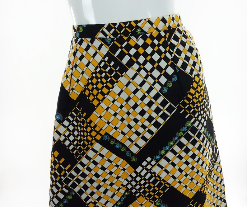 May include: A black, white, and yellow checkered skirt with a geometric pattern and small floral accents.