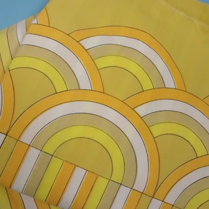 May include: A yellow and white patterned bedding set. The set includes a pillowcase and a sheet, both with a repeating design of arched shapes in shades of yellow, white, and tan. The background is a solid yellow colour.