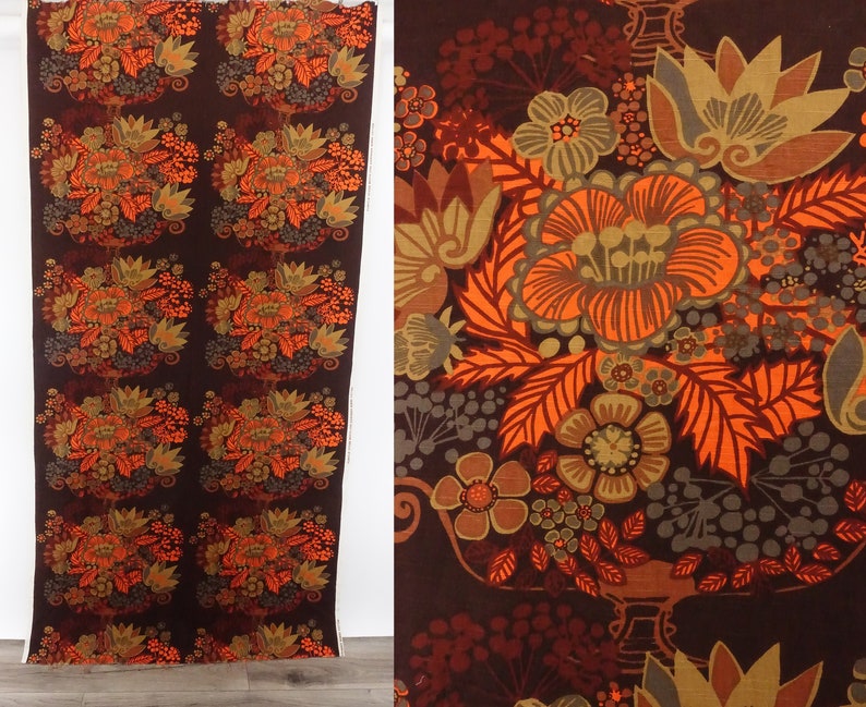 May include: A brown fabric with a repeating pattern of orange, brown, and gray stylized flowers. The fabric has a vintage feel.