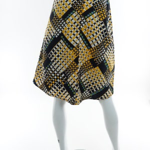 May include: A black, yellow, and white patterned skirt with a geometric design. The skirt is knee-length and has a fitted waist.