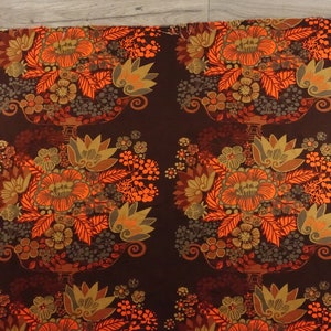 May include: A brown fabric with a repeating pattern of orange, yellow, and green floral bouquets. The fabric is about 1 yard long.