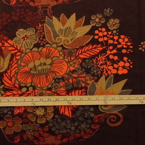 May include: A brown fabric with a repeating pattern of orange, brown, and green stylized flowers. The fabric has a vintage feel and would be great for upholstery or quilting.