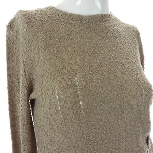 May include: A beige knitted sweater with a delicate openwork pattern. The sweater has long sleeves and a round neckline.