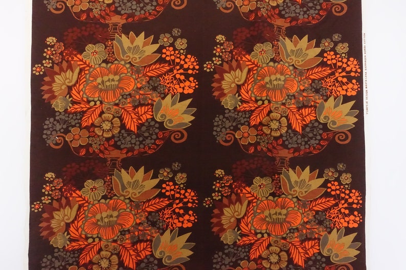 May include: A repeating pattern of orange, brown, and gold floral designs on a dark brown background. The design features stylized flowers and leaves.
