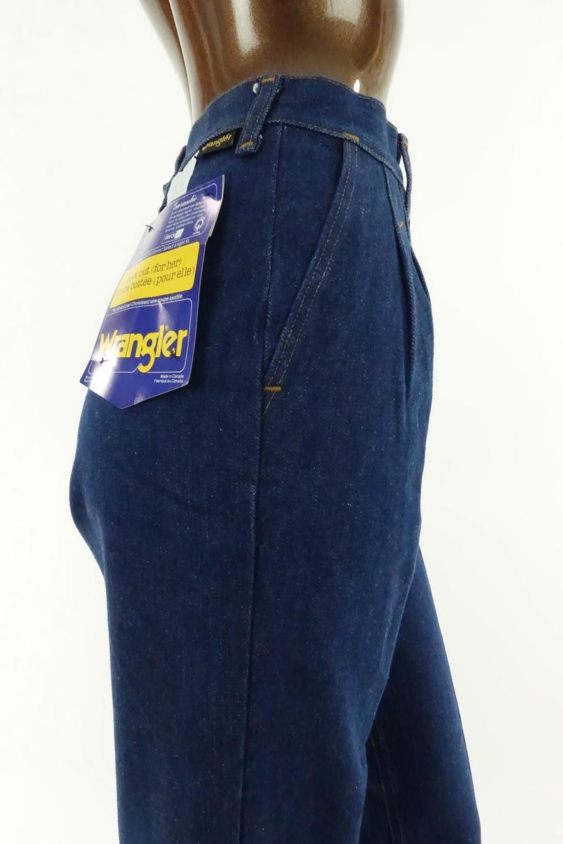 May include: A pair of dark blue denim jeans with a Wrangler label. The jeans have a high waist and a straight leg.