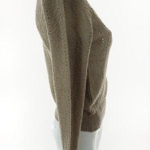 May include: A light brown knitted sweater with a V-neck and long sleeves.