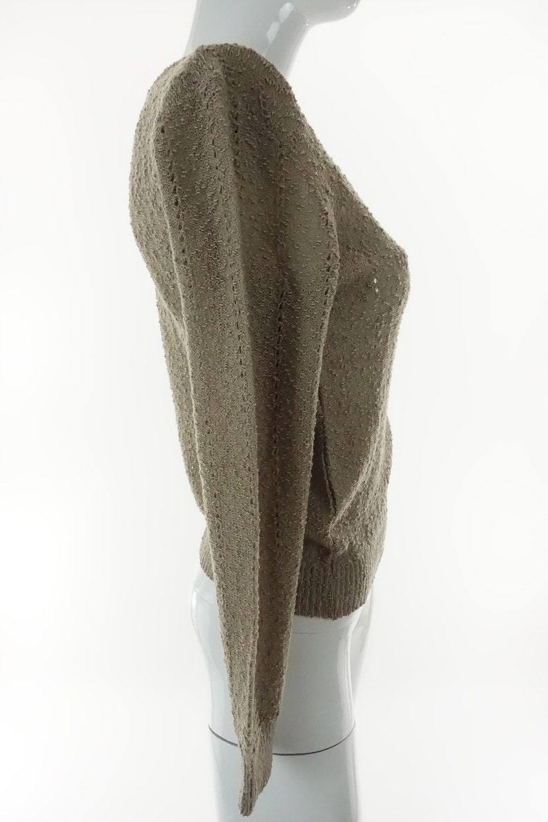 May include: A light brown knitted sweater with a V-neck and long sleeves.