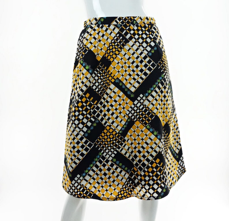May include: A black, white, and yellow patterned skirt with a geometric design. The skirt is knee-length and has a flared silhouette.