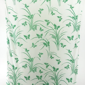 May include: White fabric with a green butterfly and grass pattern.
