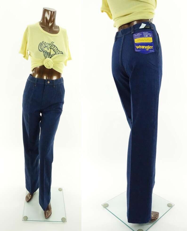 May include: A pair of dark blue denim jeans with a wide leg. The jeans have a Wrangler tag on the back pocket.