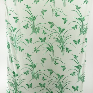 May include: White fabric with a green butterfly and grass pattern.