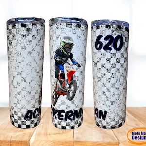 May include: Three stainless steel tumblers with a checkered pattern and a dirt bike design. The center tumbler features a photo of a child riding a dirt bike. The left tumbler has the text "ACKERMAN" and the right tumbler has the text "620 AN".