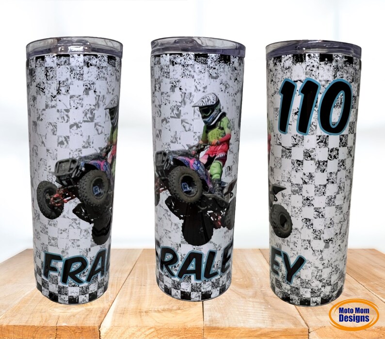 May include: A white and black checkered tumbler with a photo of a person riding an ATV. The tumbler has the name "FRALEY" and the number "110" printed on it.
