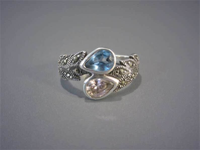 A beautiful sterling ring with a blue and pink pear cut crystal and a laurel wreath design on the sides of the band set with marcasite stones, a size six and a half. Ready to wear.
