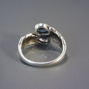 May include: A silver ring with two blue and purple stones set in a twisted band.