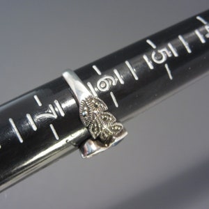 May include: A silver ring featuring a blue stone and a floral design set with marcasite stones.